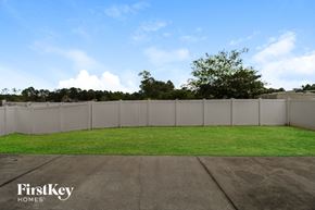Jacksonville house for rent - the backyard of a house with a white fence and grass