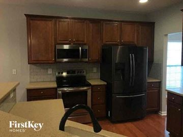 Gastonia house for rent - a kitchen with black appliances and wooden cabinets