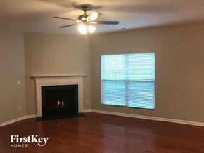 Gastonia house for rent - a living room with a fireplace and a ceiling fan