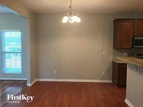 Gastonia house for rent - an empty living room with a wood floor and a chandelier