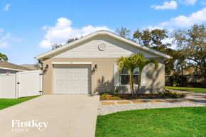 Venice house for rent - a beige house with a white garage door and a palm tree