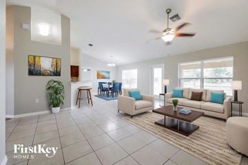 Lehigh Acres house for rent - A spacious living room with a large couch, a coffee table, and a painting on the wall.