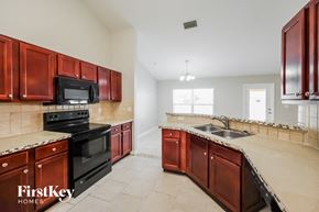 Lehigh Acres house for rent - A kitchen with red cabinets and black appliances.