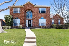 Rowlett house for rent - a red brick house with a green lawn and a black door