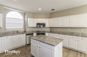 Rowlett house for rent - a kitchen with white cabinets and granite counter tops