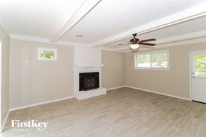 Bartlett house for rent - A spacious room with a fireplace and a ceiling fan.