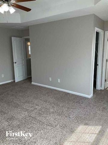 Charlotte house for rent - a living room with a white carpet and a ceiling fan