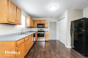 Indianapolis house for rent - a kitchen with wooden cabinets and a black refrigerator