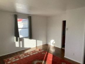 Trinidad house for rent - a empty living room with a red rug and a window