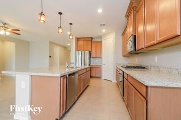 Surprise house for rent - A kitchen with wooden cabinets and a marble countertop.