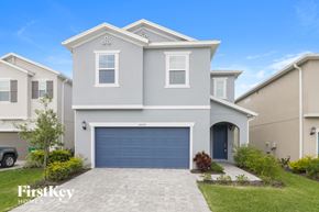 Wesley Chapel house for rent - A grey house with a blue garage door in front of a clear blue sky.