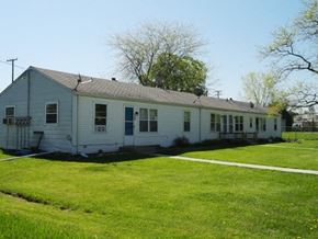 Fowlerville apartment for rent - a white house with a green lawn and trees
