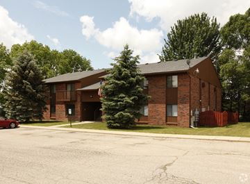 Fowlerville apartment for rent - the front of a brick apartment building with a parking lot