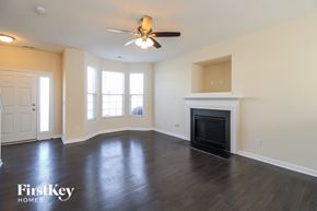Greensboro house for rent - A spacious living room with a fireplace and a ceiling fan.
