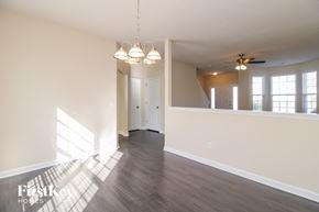 Greensboro house for rent - A spacious room with wooden floors and a ceiling fan.
