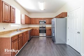 Greensboro house for rent - A kitchen with wooden cabinets and a grey refrigerator.
