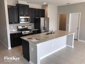 Riverview house for rent - an empty kitchen with black cabinets and a counter top