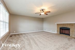 Clarksville house for rent - A spacious room with a fireplace and a ceiling fan.