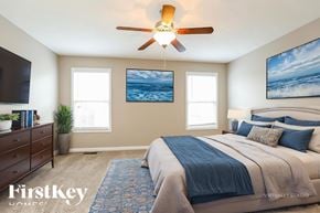Clarksville house for rent - A bedroom with a large bed and a ceiling fan.