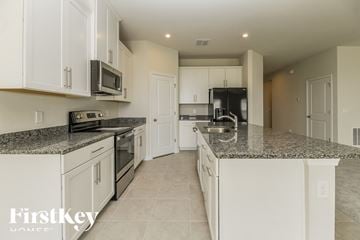 Minneola house for rent - a large kitchen with white cabinets and granite counter tops