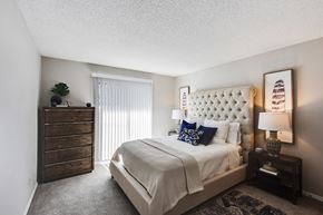 Smyrna apartment for rent - A bedroom with a large bed, a wooden dresser, and a lamp on a side table.