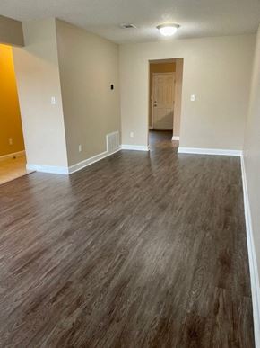 Pensacola house for rent - A room with a wooden floor and a door.