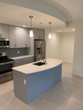 Winnipeg apartment for rent - an open kitchen with a blue island and stainless steel appliances