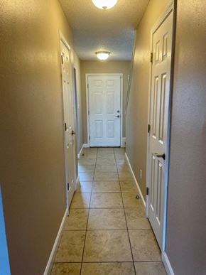 Pensacola house for rent - a hallway with a white door and a tile floor