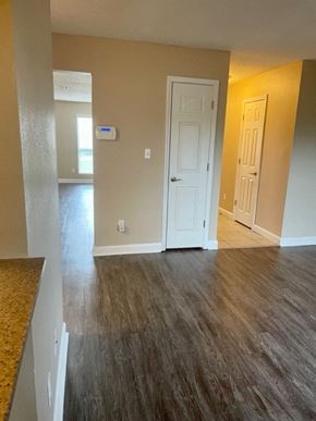 Pensacola house for rent - an empty living room with wood floors and a white door