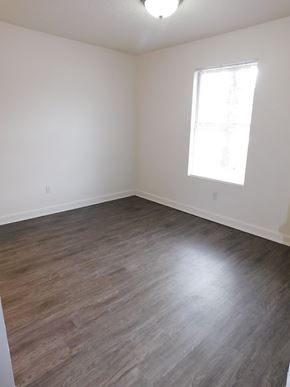 Pensacola house for rent - A room with a window and wooden flooring.