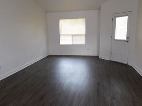 Pensacola house for rent - A room with a wooden floor and a window with blinds.