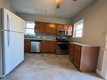 San Antonio apartment for rent - A kitchen with brown cabinets and a white refrigerator.