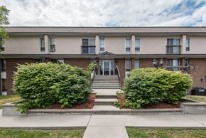 Ottawa apartment for rent - A building with a grey roof and a white wall with windows and doors.