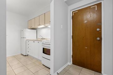 Ottawa apartment for rent - A kitchen with white appliances and a wooden door.