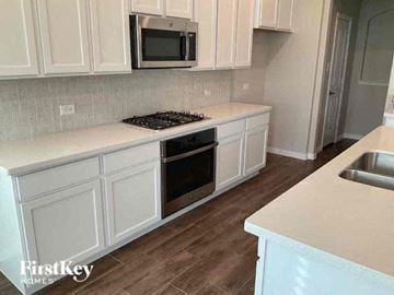Haslet house for rent - a kitchen with white cabinets and a stove and a microwave