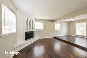 Irving house for rent - an empty living room with a fireplace and wooden floors