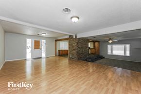 Waxahachie house for rent - A spacious room with wooden floors and a stone wall.