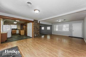 Waxahachie house for rent - A spacious living room with wooden floors and a stone pillar.