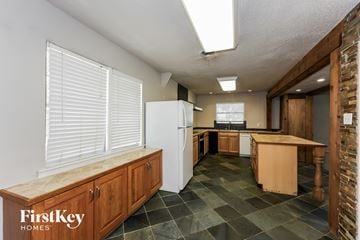 Waxahachie house for rent - A kitchen with a white fridge and wooden cabinets.