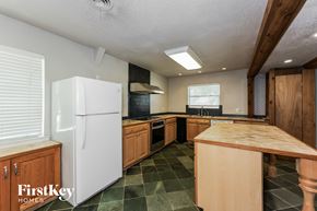 Waxahachie house for rent - A kitchen with a white fridge and wooden cabinets.