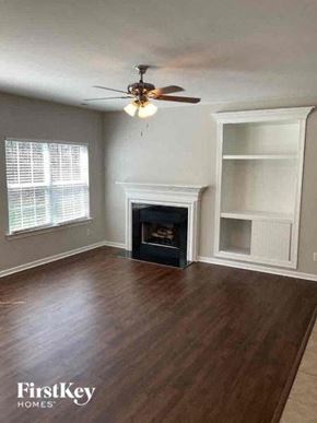 Charlotte house for rent - a empty living room with a ceiling fan and a fireplace