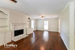 Collierville house for rent - an empty living room with a fireplace and wooden floors