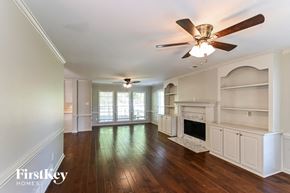 Collierville house for rent - an empty living room with a ceiling fan and a fireplace