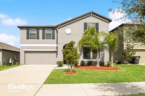 Wimauma house for rent - a beige house with a lawn and palm trees