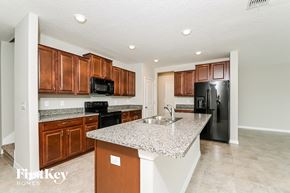 Wimauma house for rent - a kitchen with granite countertops and black appliances