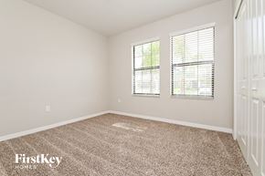 Wimauma house for rent - a bedroom with a carpeted floor and two windows