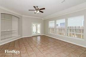 Cypress house for rent - A spacious room with a ceiling fan and sliding glass doors.