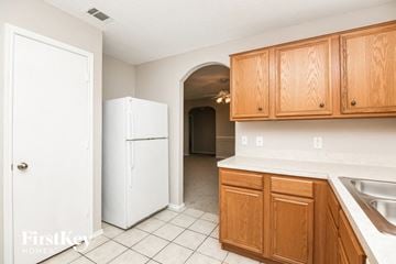 Fort Worth house for rent - A kitchen with wooden cabinets and a white fridge.