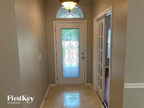 Orange Park house for rent - A white door with a stained glass window is in a hallway with a light on.