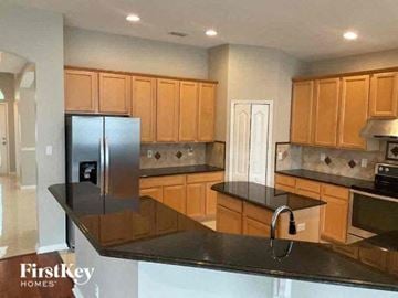 Orange Park house for rent - A kitchen with wooden cabinets and a black countertop.